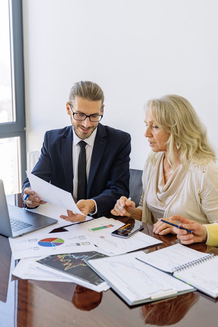 Solertia Management Ltd Two business professionals reviewing financial documents and graphs during a meeting.